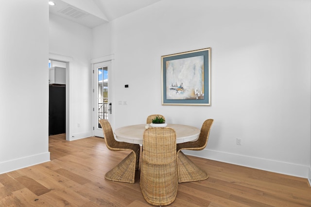 dining space featuring vaulted ceiling and light hardwood / wood-style floors