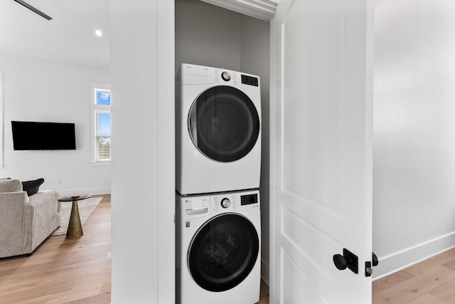 washroom with light hardwood / wood-style flooring and stacked washer / drying machine