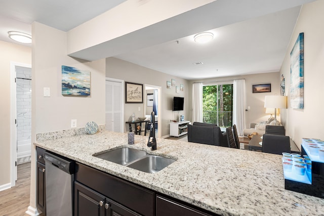 kitchen featuring dark brown cabinets, light hardwood / wood-style floors, dishwasher, light stone counters, and sink