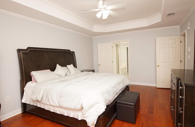 bedroom featuring wood-type flooring, a tray ceiling, ceiling fan, and ornamental molding