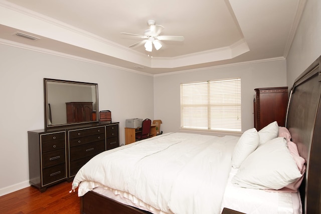 bedroom with a tray ceiling, ceiling fan, crown molding, and dark wood-type flooring