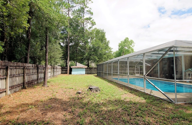 view of swimming pool featuring a lawn, glass enclosure, and a storage unit