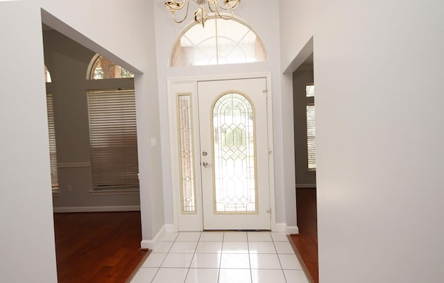 tiled foyer featuring a high ceiling and an inviting chandelier