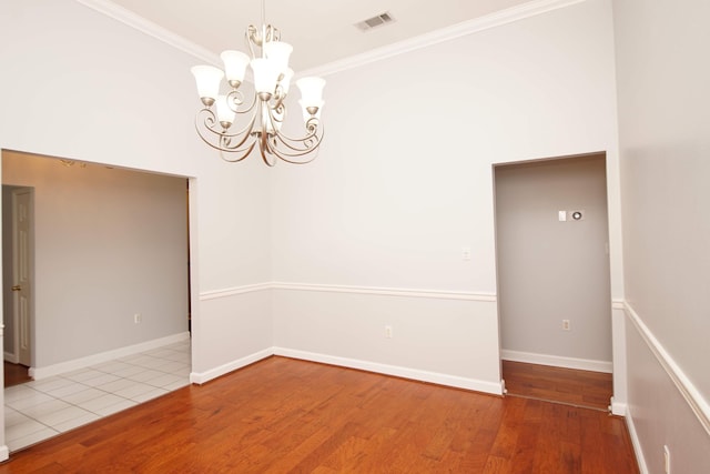 unfurnished room with hardwood / wood-style floors, ornamental molding, and a notable chandelier