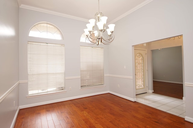 spare room featuring light hardwood / wood-style flooring, an inviting chandelier, and crown molding