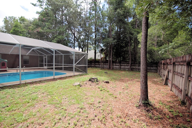 view of yard with a fenced in pool and glass enclosure