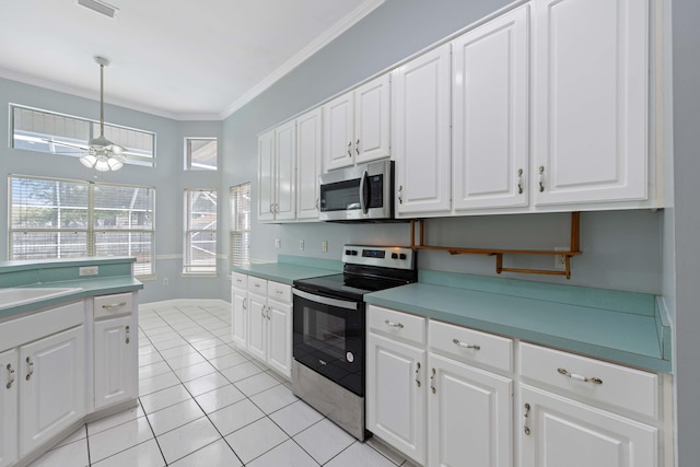 kitchen with pendant lighting, ornamental molding, stainless steel appliances, and white cabinets