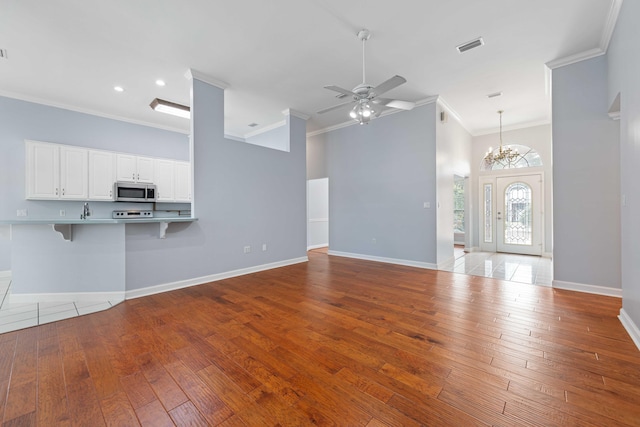 unfurnished living room with crown molding, ceiling fan with notable chandelier, and light hardwood / wood-style flooring