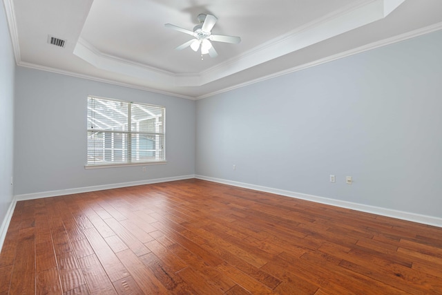 empty room featuring ornamental molding, hardwood / wood-style floors, ceiling fan, and a tray ceiling