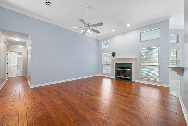 unfurnished living room featuring ceiling fan, crown molding, a fireplace, and wood-type flooring