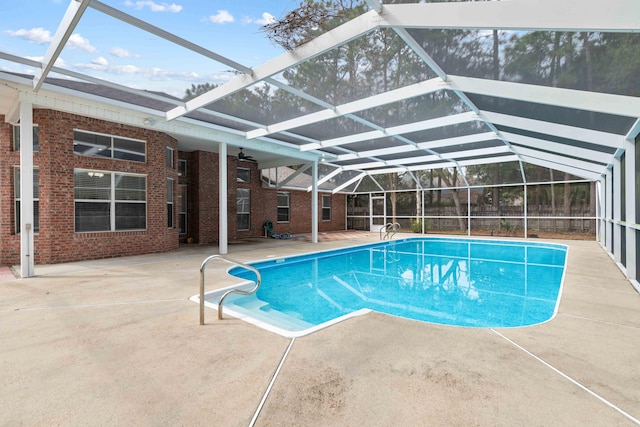 view of pool with ceiling fan, glass enclosure, and a patio area