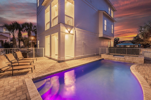 pool at dusk with a patio area