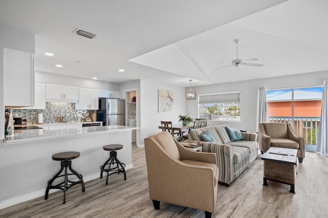 living room with a wealth of natural light, light hardwood / wood-style floors, and ceiling fan