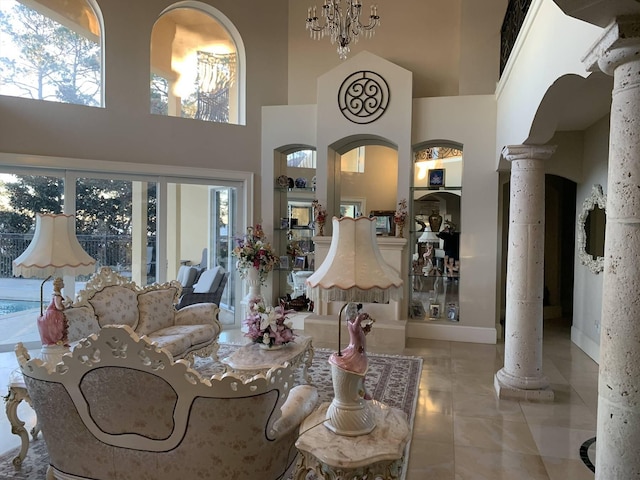 tiled living room featuring a chandelier, a high ceiling, and decorative columns