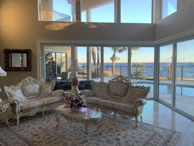 tiled living room with a towering ceiling and a water view