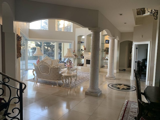 living room featuring ornate columns, light tile patterned floors, and a high ceiling