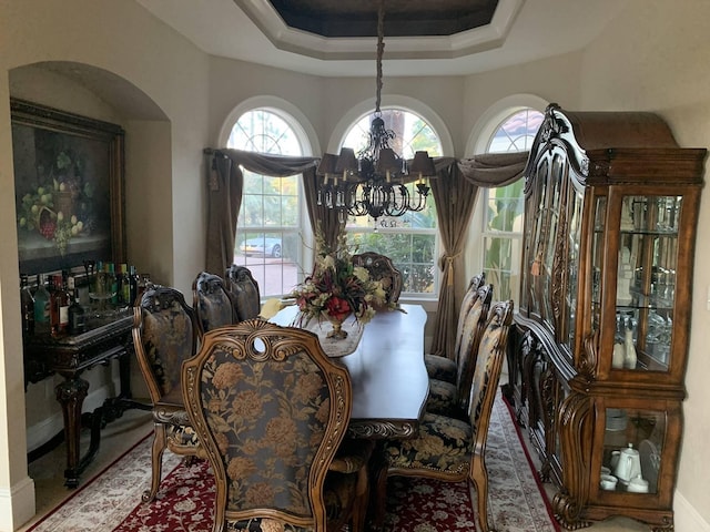 dining room featuring a raised ceiling and a notable chandelier