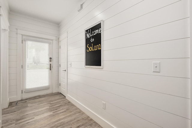 entryway with light hardwood / wood-style flooring and wood walls