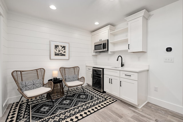 sitting room with light hardwood / wood-style floors, sink, and beverage cooler