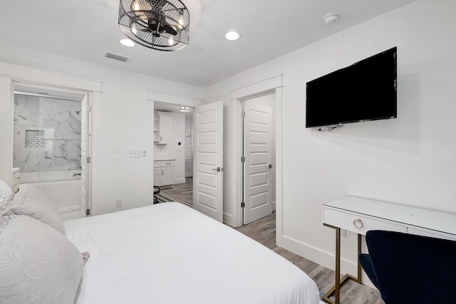 bedroom featuring light hardwood / wood-style flooring, ensuite bathroom, and an inviting chandelier