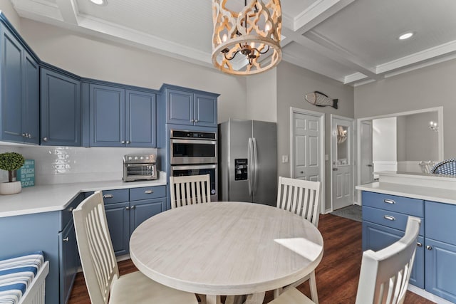 kitchen with appliances with stainless steel finishes, coffered ceiling, a notable chandelier, tasteful backsplash, and dark hardwood / wood-style flooring