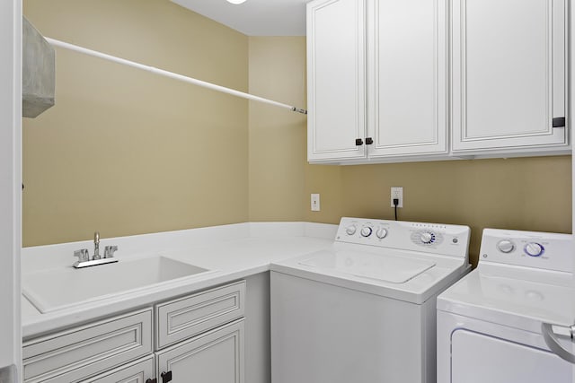 clothes washing area featuring washer and dryer, cabinets, and sink