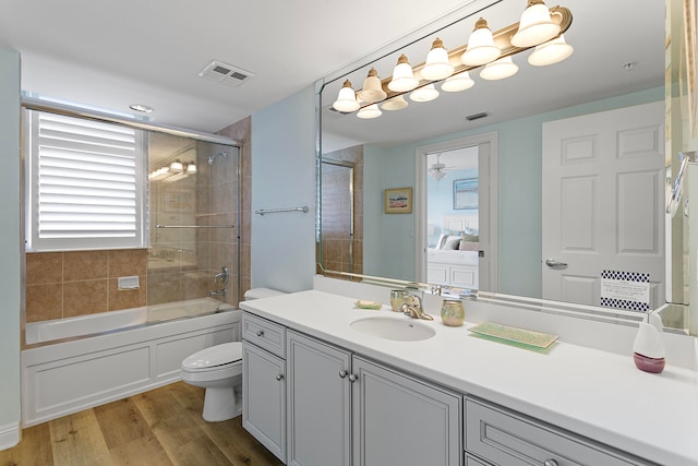 full bathroom with hardwood / wood-style flooring, a healthy amount of sunlight, toilet, and shower / bath combination with glass door