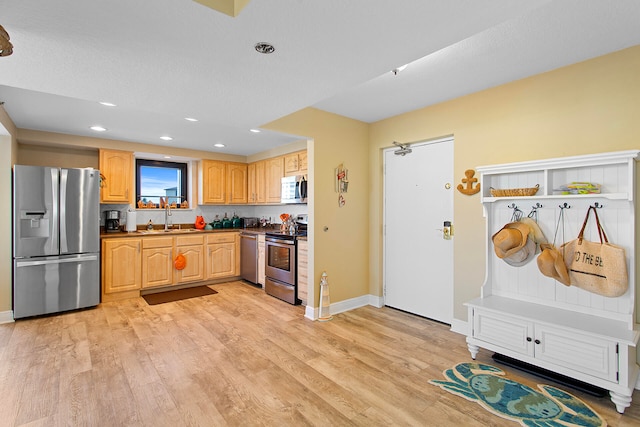 kitchen featuring baseboards, dark countertops, stainless steel appliances, light wood-type flooring, and a sink