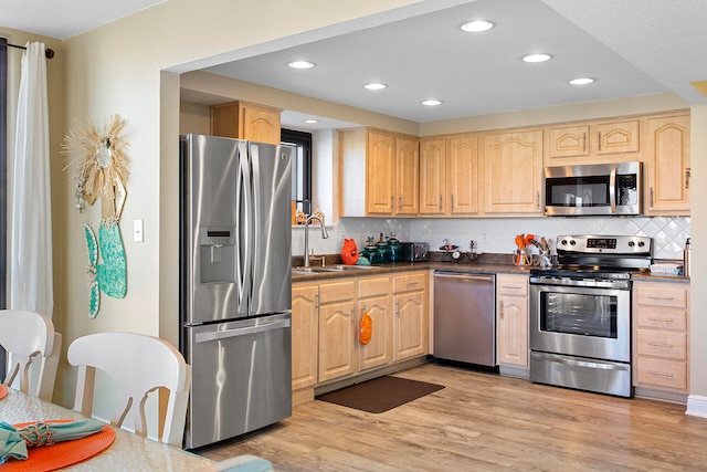 kitchen with stainless steel appliances, dark countertops, and light brown cabinets