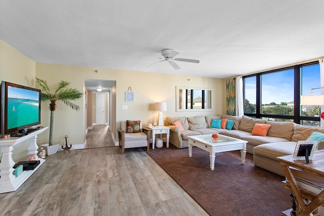 living area with plenty of natural light, a textured ceiling, ceiling fan, and wood finished floors