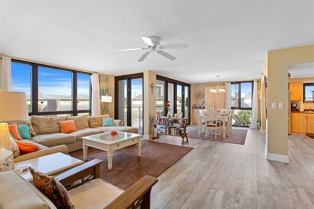 living area featuring a wealth of natural light, baseboards, light wood-style flooring, and a textured ceiling