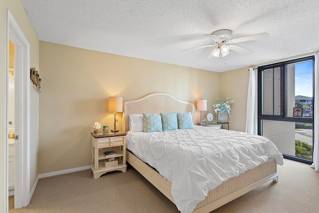 bedroom with carpet flooring, a textured ceiling, baseboards, and multiple windows