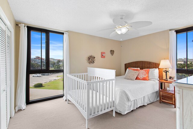 bedroom featuring expansive windows, light carpet, ceiling fan, and a textured ceiling