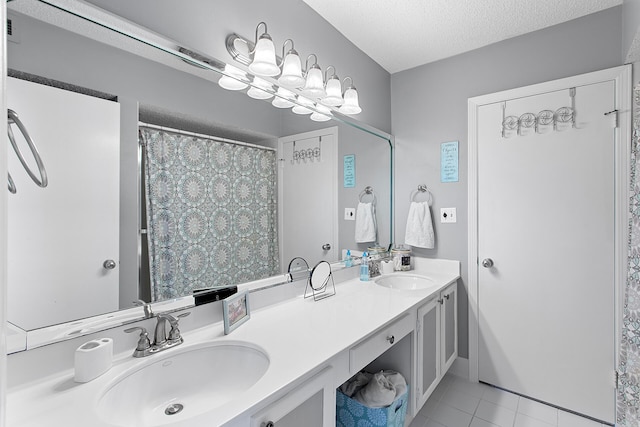 full bathroom featuring a textured ceiling, double vanity, tile patterned flooring, and a sink