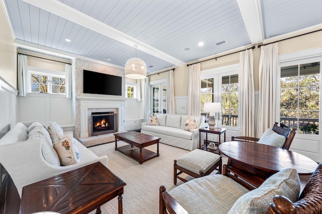 living room with beamed ceiling, wooden ceiling, and a premium fireplace