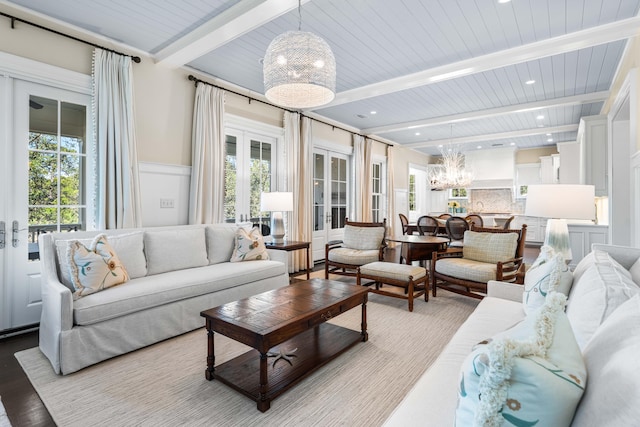 living room featuring beamed ceiling, a notable chandelier, and a wealth of natural light