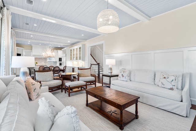 living room featuring beam ceiling and an inviting chandelier