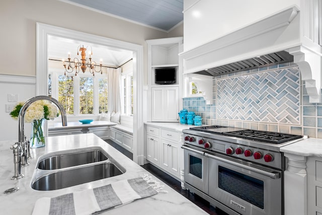 kitchen with range with two ovens, backsplash, ornamental molding, custom range hood, and a notable chandelier