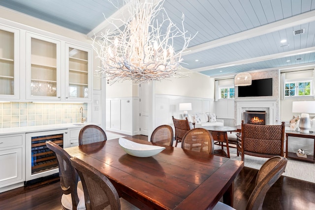 dining room with beverage cooler, beam ceiling, dark wood-type flooring, and plenty of natural light