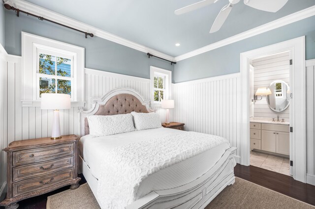 bedroom with ensuite bath, dark hardwood / wood-style floors, ornamental molding, sink, and ceiling fan