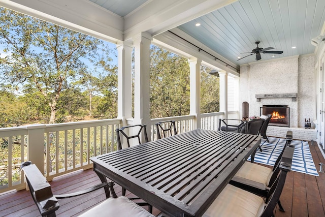 deck with ceiling fan and an outdoor brick fireplace