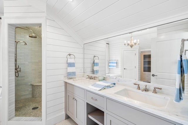 bathroom with vanity with extensive cabinet space, dual sinks, a chandelier, a shower with shower door, and vaulted ceiling