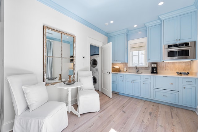 kitchen with oven, light hardwood / wood-style floors, backsplash, stacked washing maching and dryer, and crown molding