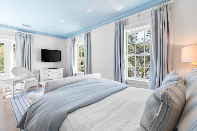 bedroom with light hardwood / wood-style flooring, ceiling fan, and ornamental molding