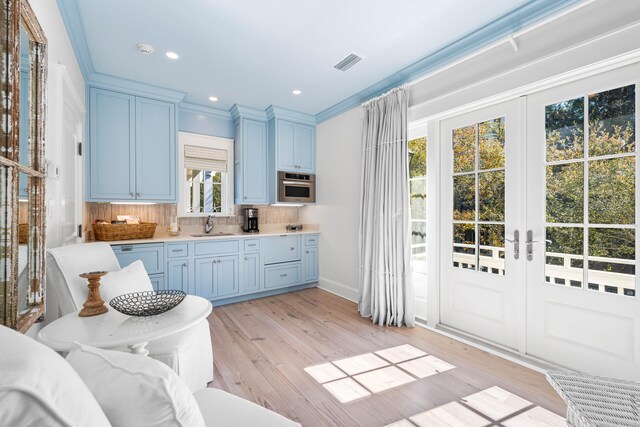 kitchen with backsplash, light hardwood / wood-style flooring, french doors, and stainless steel oven