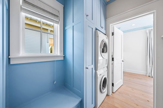 laundry area featuring light hardwood / wood-style floors and stacked washing maching and dryer