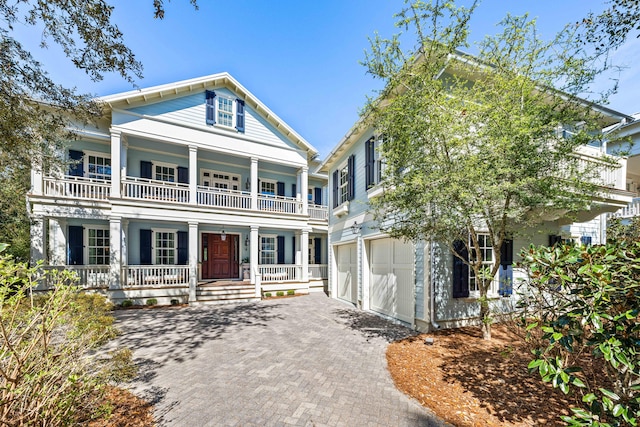 greek revival house featuring a garage, a porch, and a balcony