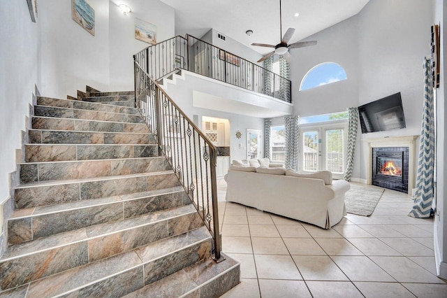 stairs with high vaulted ceiling, ceiling fan, and light tile flooring