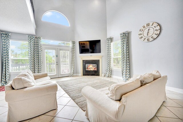 tiled living room featuring french doors, a brick fireplace, a towering ceiling, and a textured ceiling