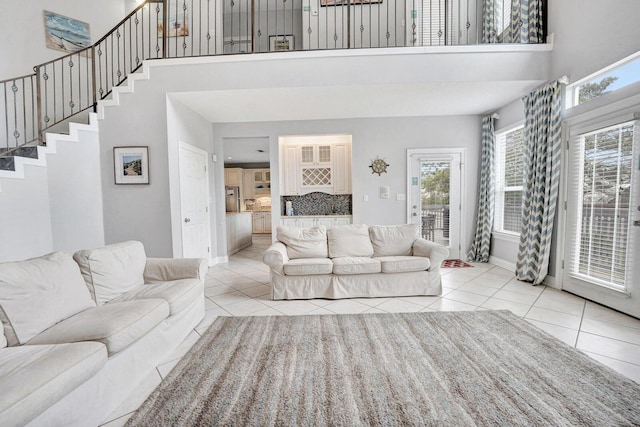 living room featuring a healthy amount of sunlight, a towering ceiling, and light tile floors